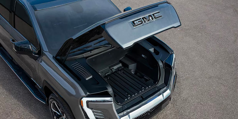 A top view of a 2025 GMC Sierra EV truck with the hood open, revealing an empty storage space.